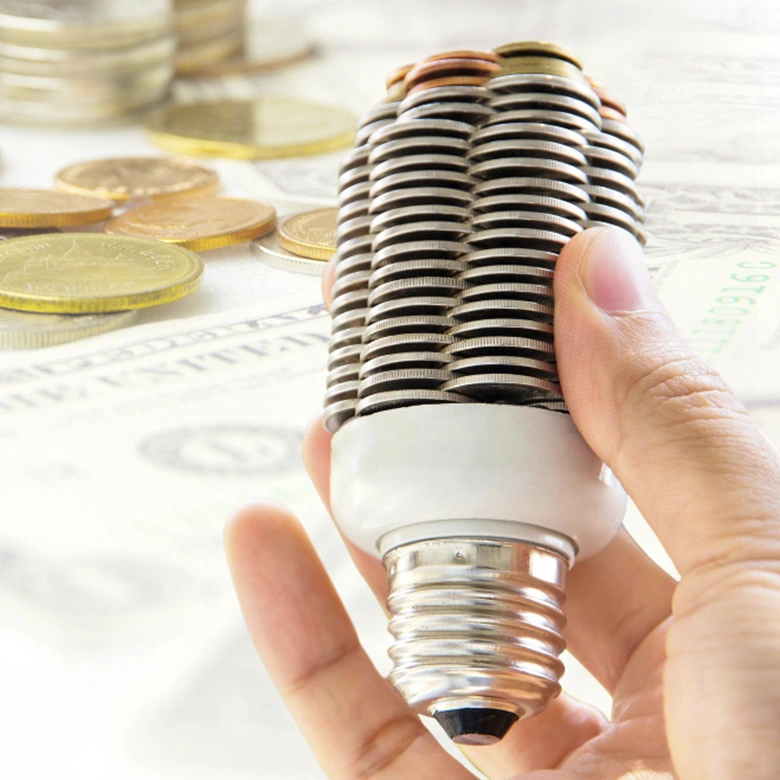 mano sujetando bombilla con monedas euro